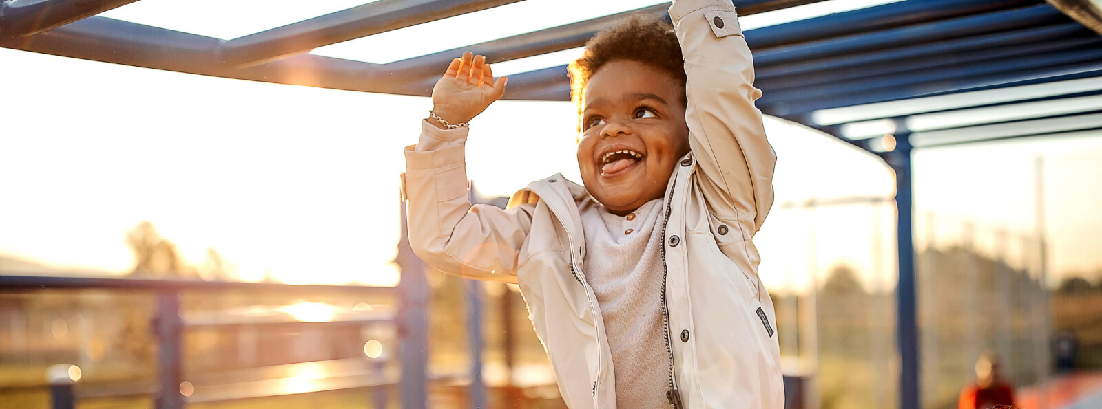 a young kid swinging on monkey bars at a playground